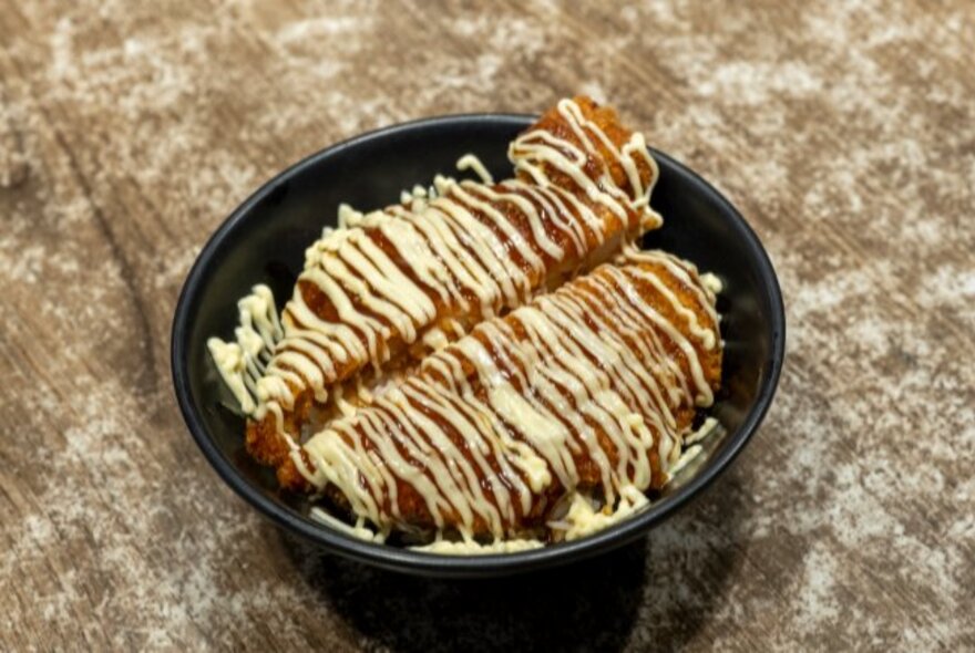 A dish of Japanese meat drizzled with mayonnaise.