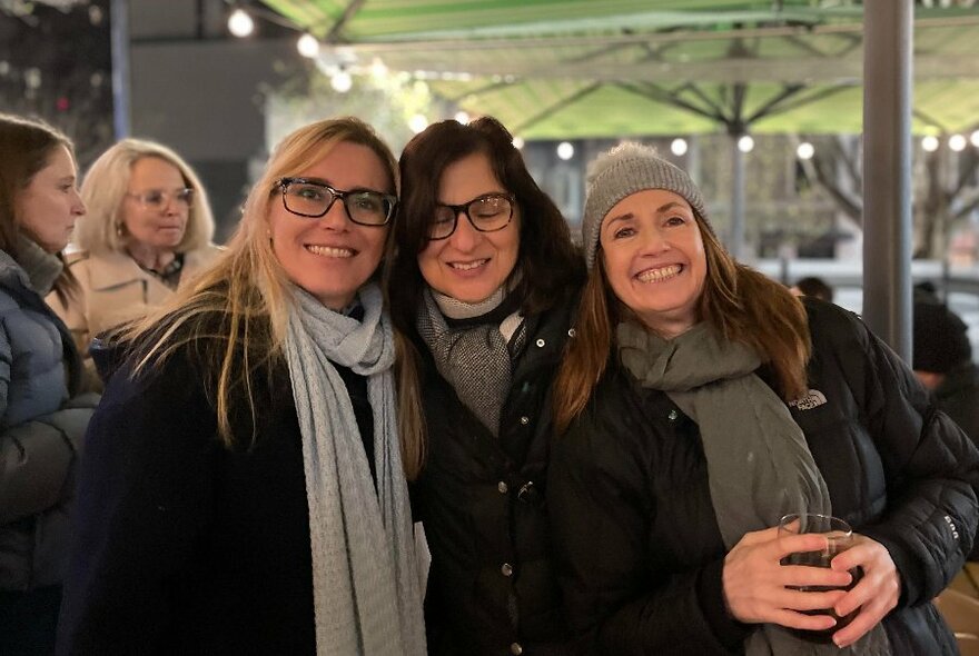 Several people standing in an outdoor courtyard smiling and enjoying a drink.