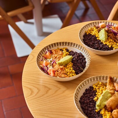 A light oak table with four burrito bowls.