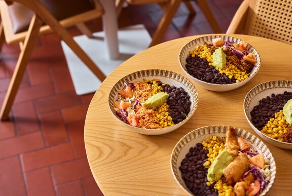 A light oak table with four burrito bowls.