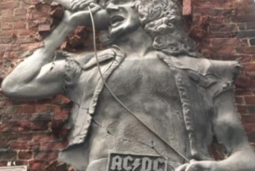 Statue of Bon Scott from AC-DC on a brick wall.