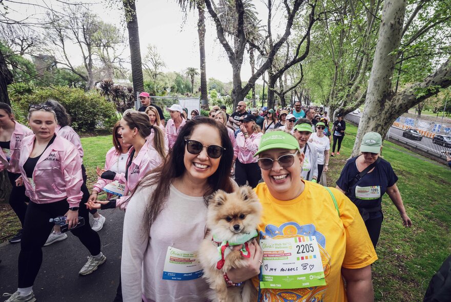 People walking as part of a charity run, wearing labels and carrying a small dog.