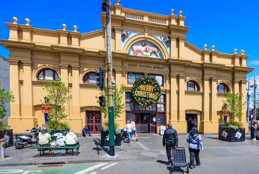 Outside a meat market on a sunny day. There is a Christmas wreath hanging on the front door. 