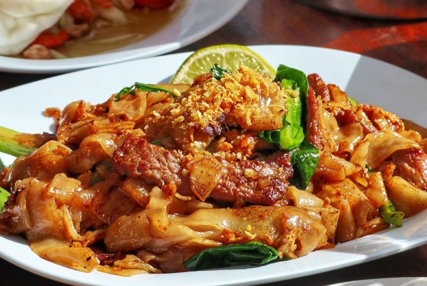 Plate of food with chilli and lemon on top, in white dish, other dishes just visible behind.