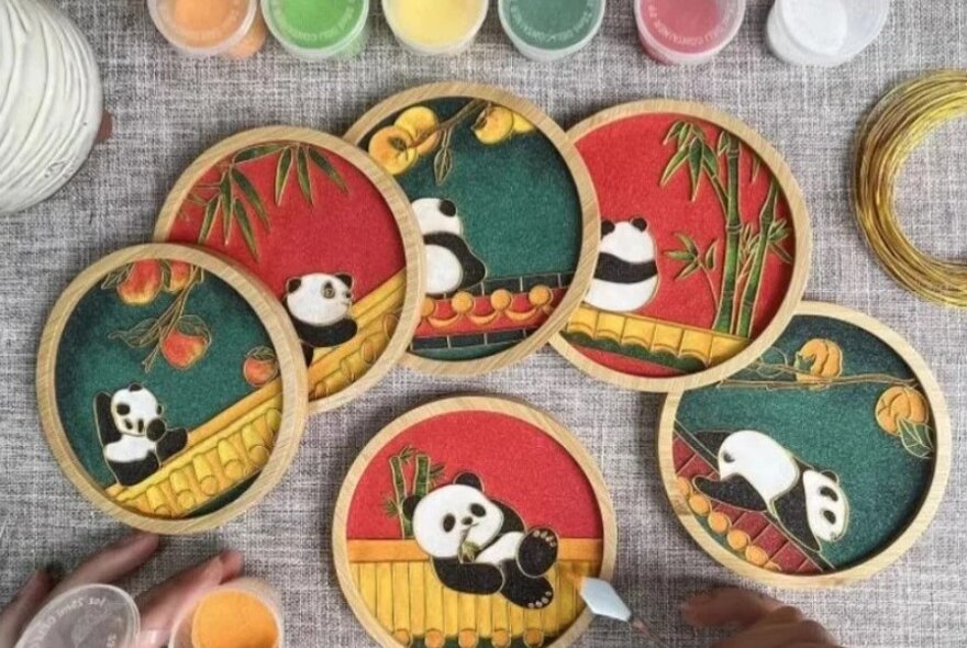 Six panda coasters in shades of green and red.