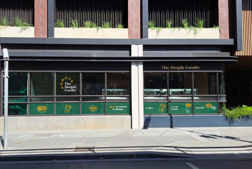 The exterior of The Simple Foodie, with green signage in a plain office building. 