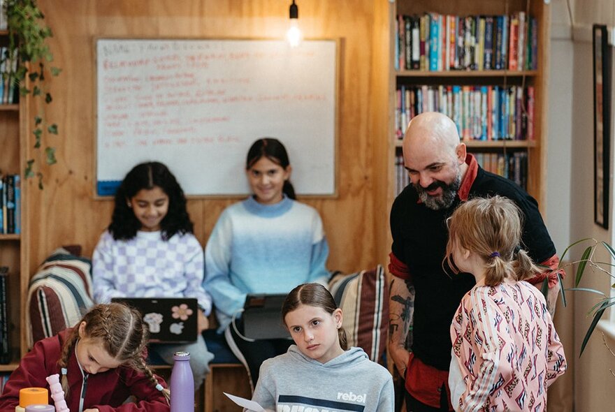 Kids in a classroom setting with a teacher looking on. 