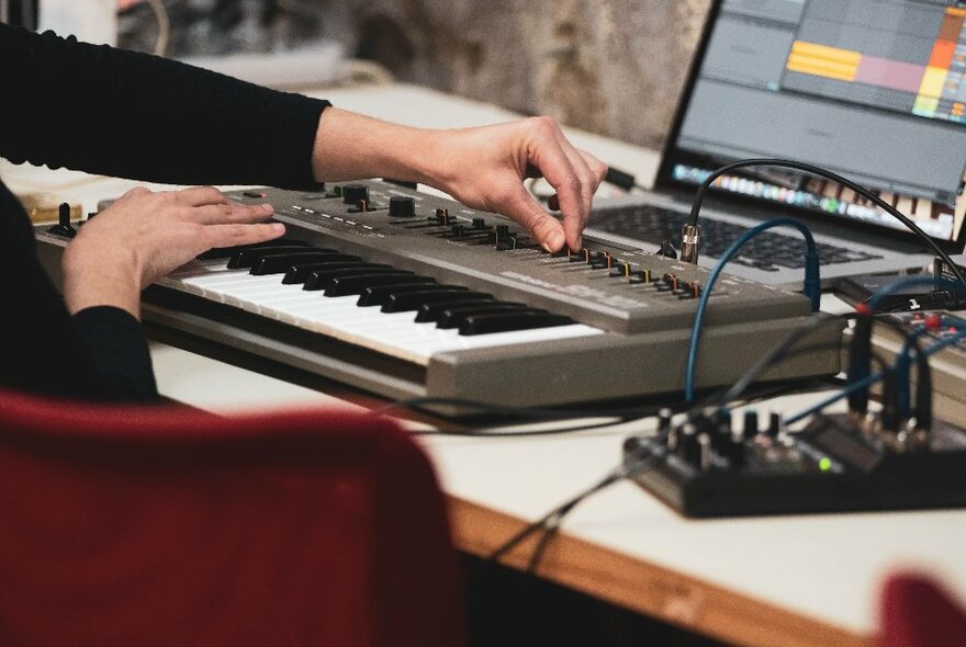 Hands over mixing deck, blurred red chair in foreground.