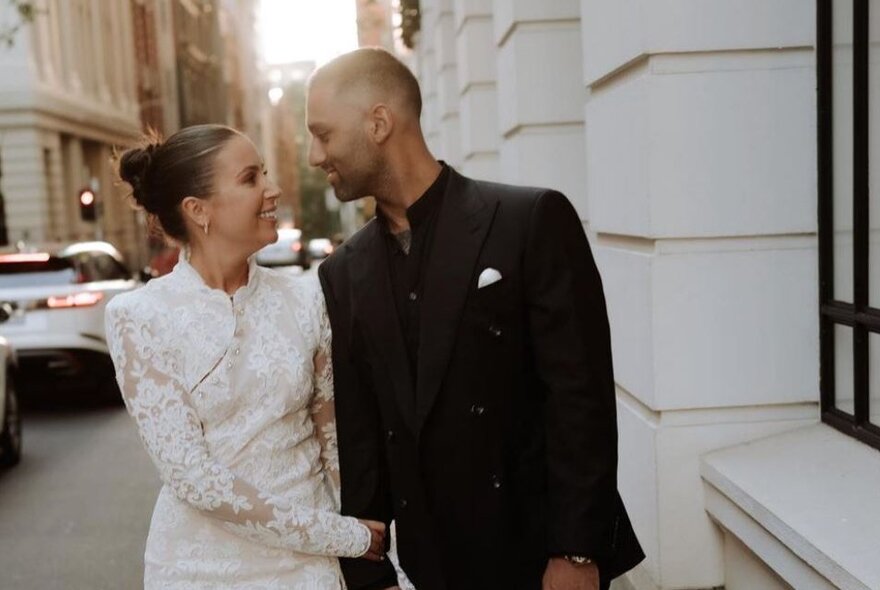 A wedding couple walking closely together in a Melbourne street, looking into each other's eyes and smiling.