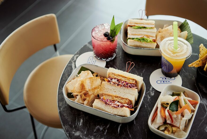 Assorted sandwiches with varied fillings, and crisps, in three plates on a round table.