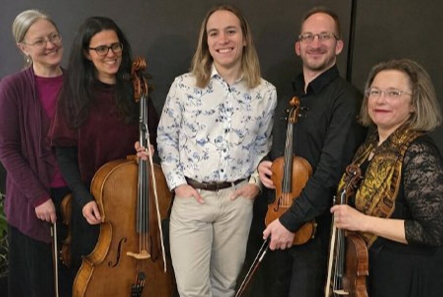 Members of the string ensemble The Crossing Machine posing with their string instruments.