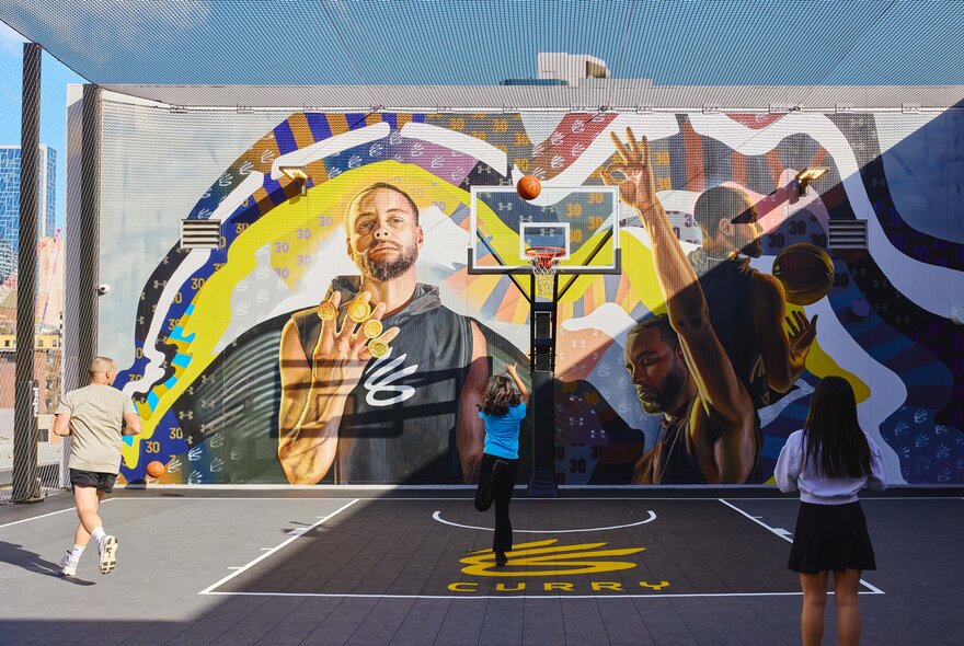 Three people playing basketball on a rooftop basketball court.