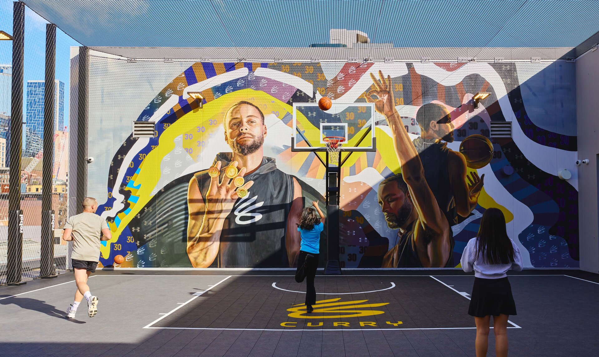 Three people playing basketball on a rooftop basketball court.