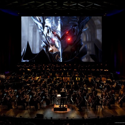 A dark image of the Melbourne Symphony Orchestra performing while a large screen displays a film on the background. 