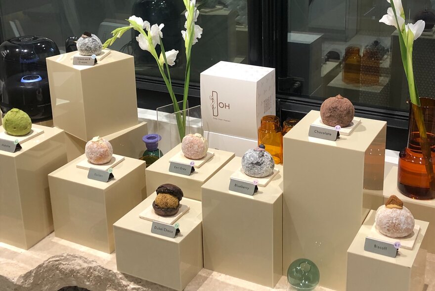 A display of different coloured filled donuts on plinths of varying sizes. 