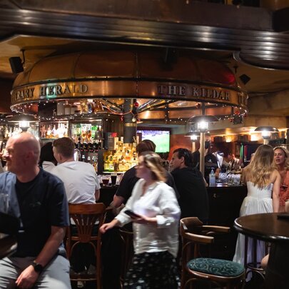 People inside PJ O'Brien's pub, most of them mingling at the bar. 