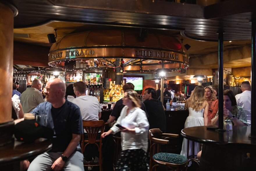 People inside PJ O'Brien's pub, most of them mingling at the bar. 