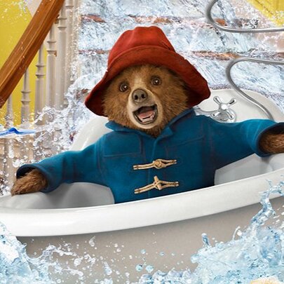 A still from the movie, Paddington, showing a bear in a blue duffel coat and a red hat floating down the stairs in a bathtub.