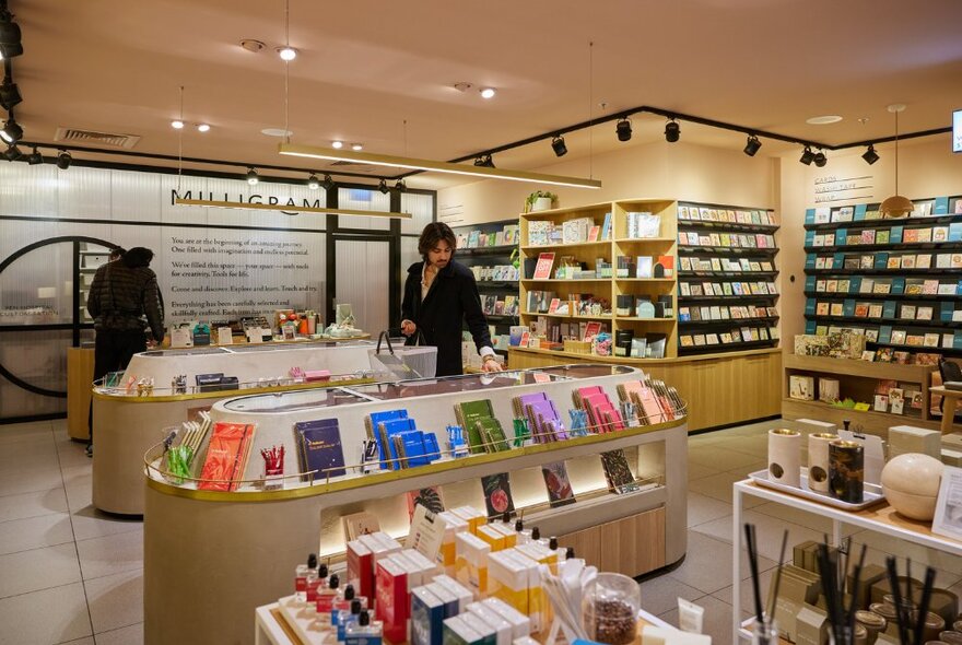 Brunette man browsing stationery in a light and bright store.