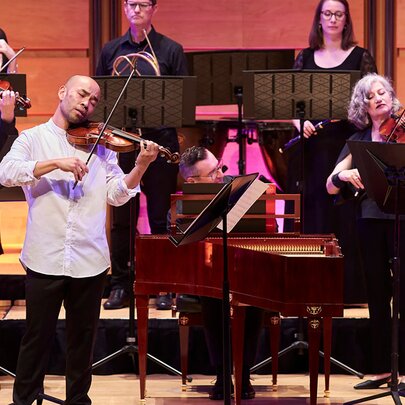 A group of orchestra musicians performing live on stage. 