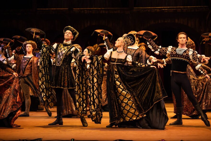 A grand ballroom scene with several dancers in elaborate Renaissance-style costumes, during a performance of Romeo and Juliet by The Australian Ballet.