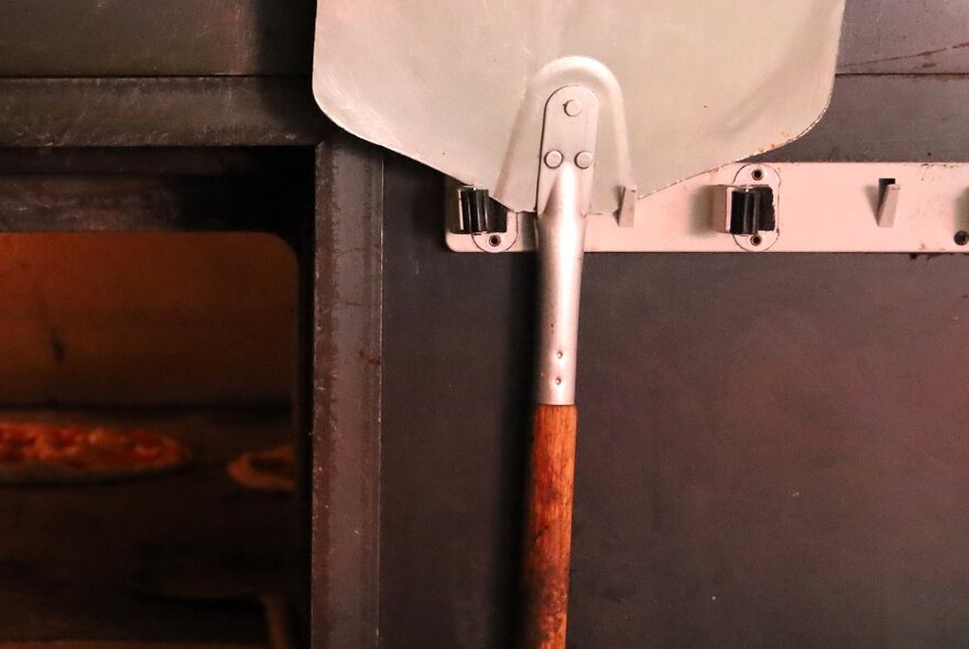 A long handled paddle used for picking up pizzas inside a pizza oven.