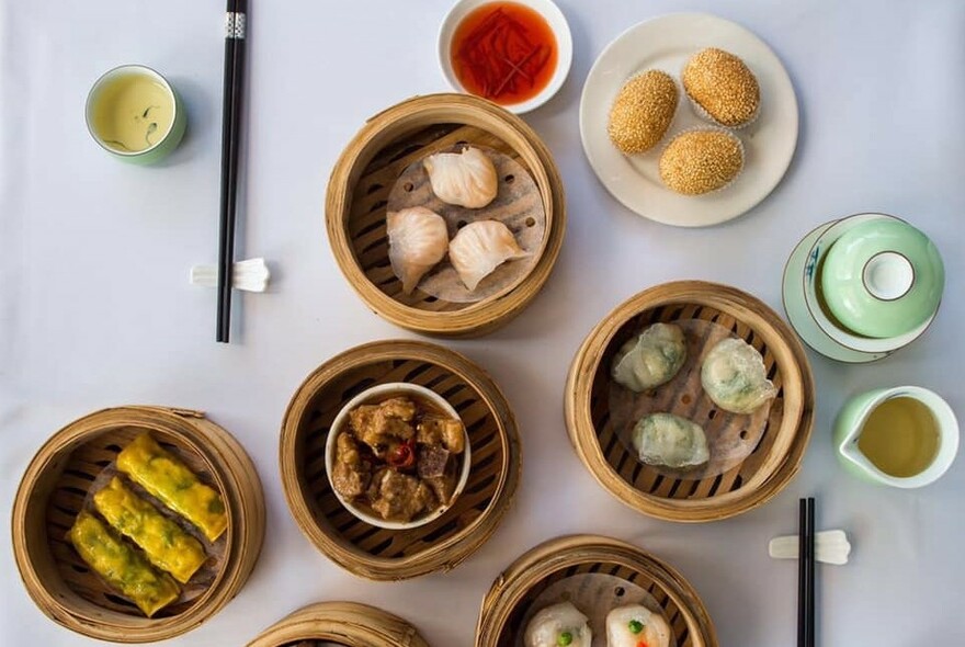 Looking straight down on a table with lots of steamers filled with dumplings.