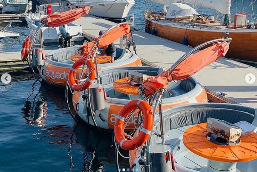 Four round orange Aqua Donut boats floating in the water.