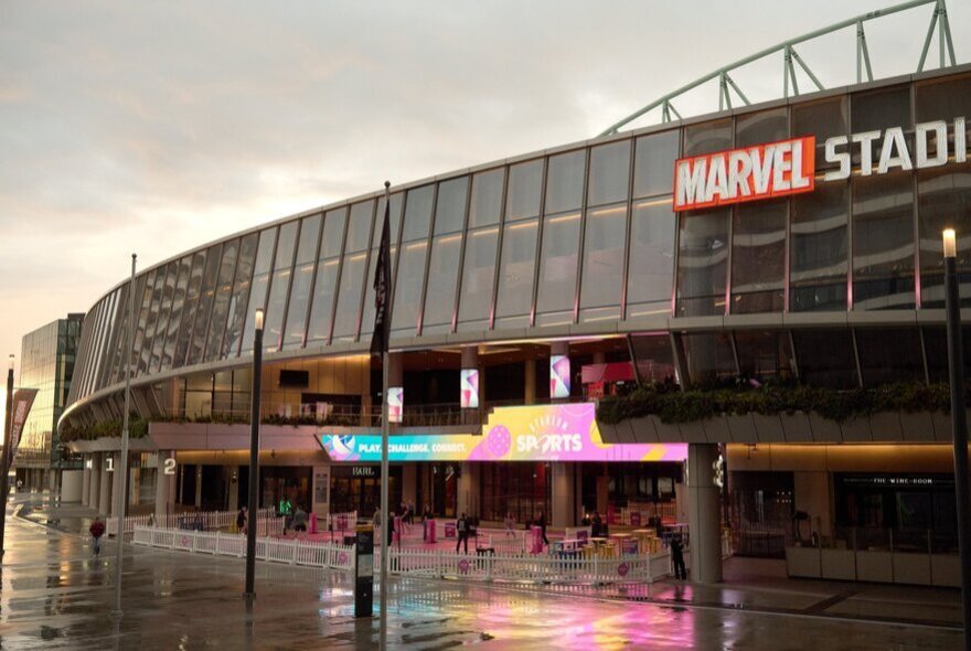 The exterior of Marvel Stadium at twilight with signage and the entrance to Sports Stadium.