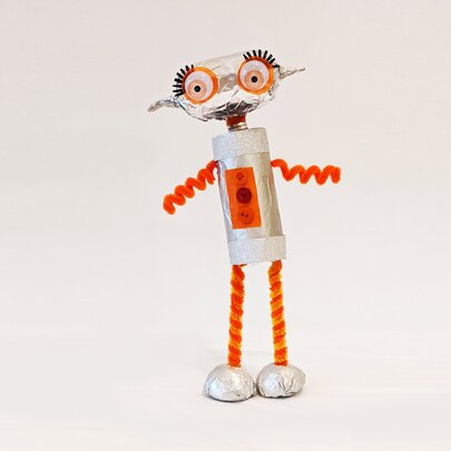 A crafted robot figurine with red legs and arms and big eyes with long eyelashes.
