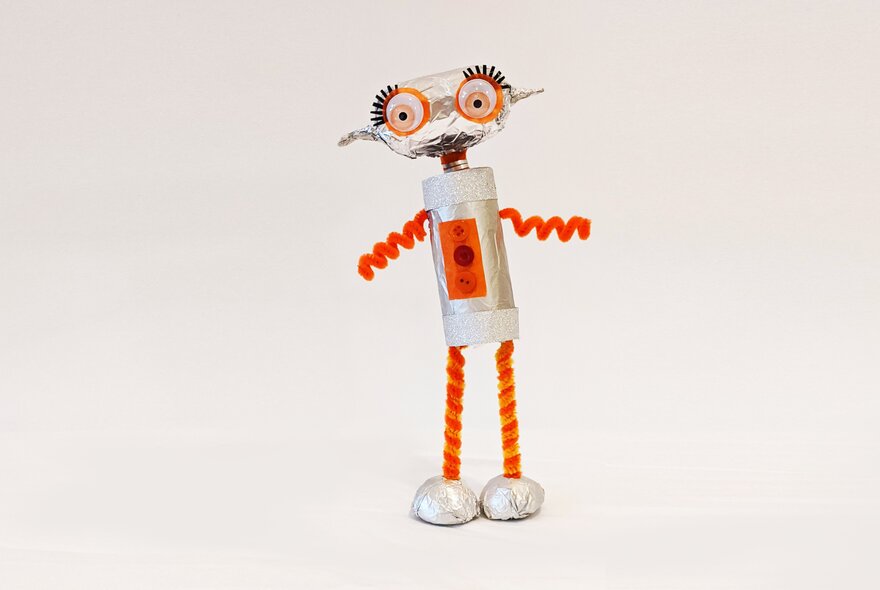 A crafted robot figurine with red legs and arms and big eyes with long eyelashes.
