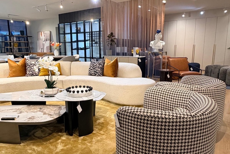 Interior of a furniture store with houndstooth tub chairs and a large white sofa. 