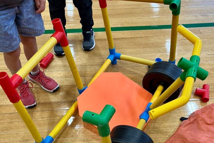 A child's wheeled creation built with large yellow pipes and colourful connectors.