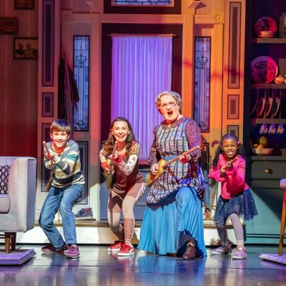 A scene from Mrs Doubtfire The Musical with the protagonist dancing with three children. 