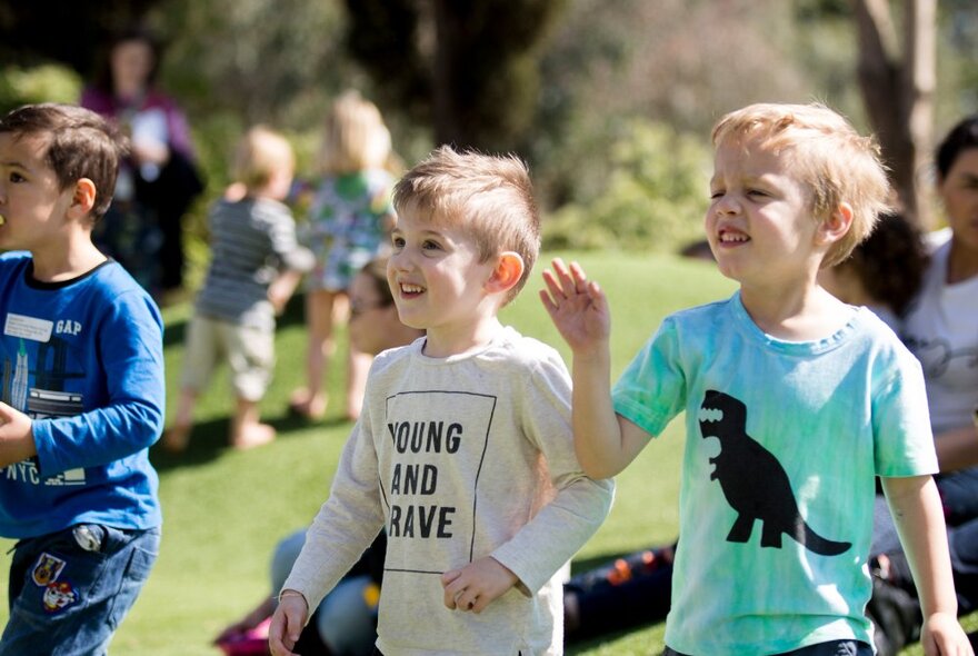 Young children smiling and dancing on the lawns at Melbourne Zoo.