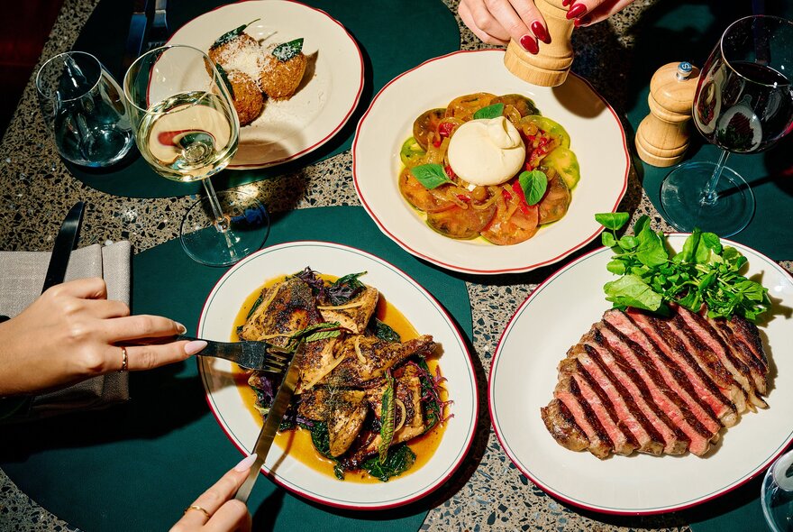 Overhead view of four dishes on a restaurant table, including slides meats.