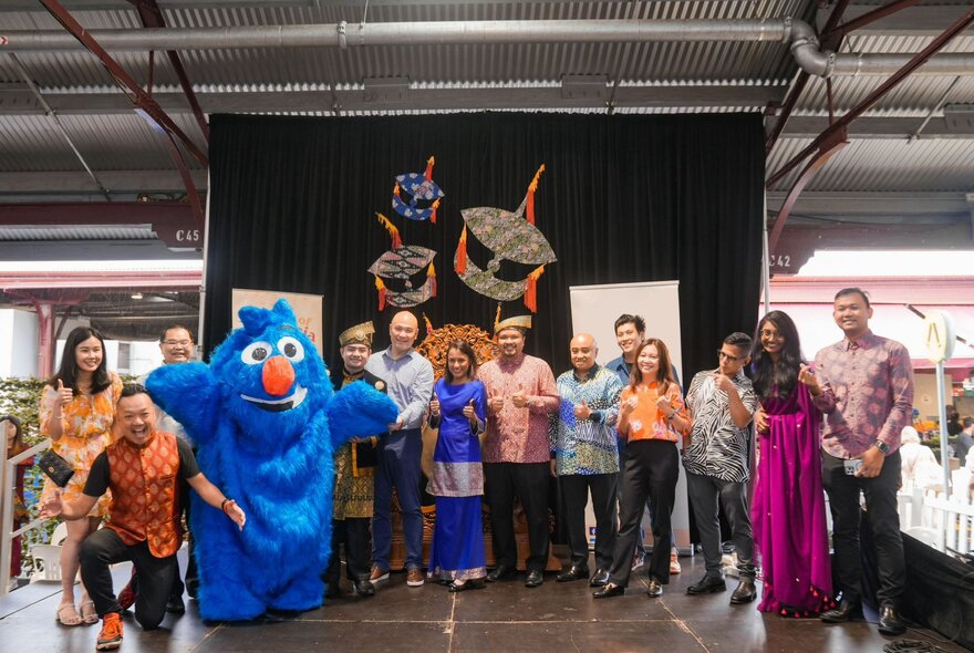 A group of people lined up at the Colours of Malaysia festival, at stage, smiling for a group photo.