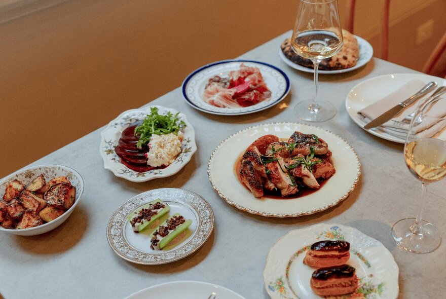 A selection of dishes of food on a table with cutlery and glasses, at Hazel restaurant.