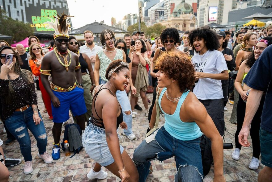 Crowds of people dancing and enjoying themselves at an outdoor festival in Fed Square.