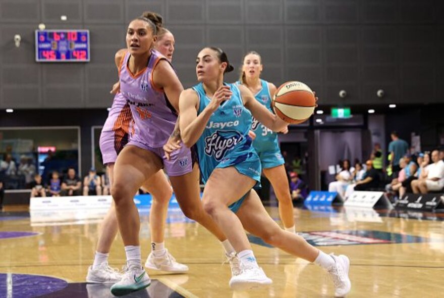 Female basketballers during a game in an indoor stadium.