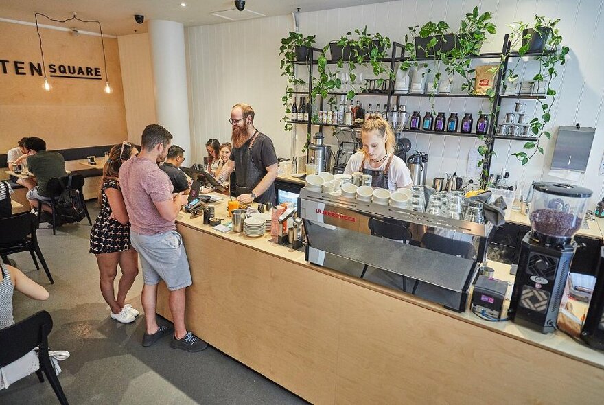 Two staff members making coffee and serving customers.