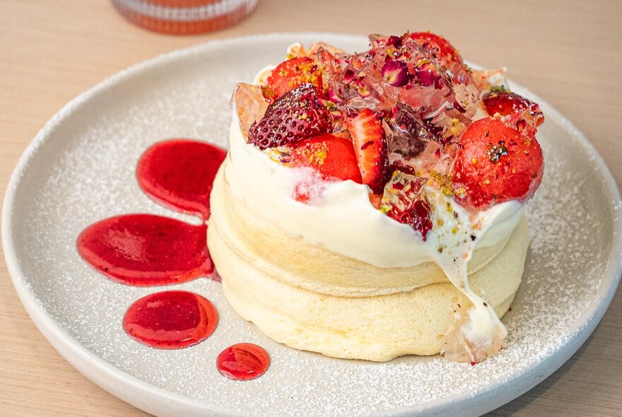 Souffle-style fluffy pancakes topped with cream, strawberries and a dusting of icing sugar. 