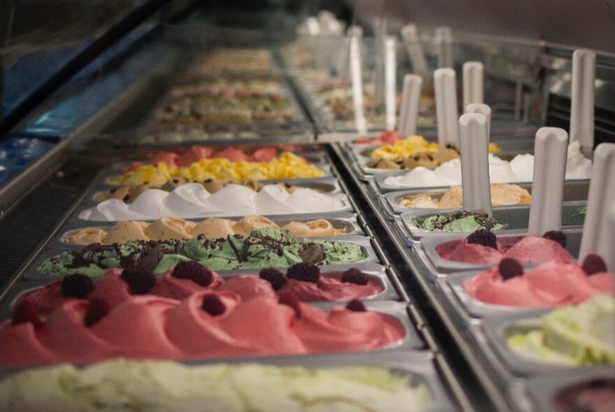 A selection of colourful gelato tubs in a ridge each with toppings.