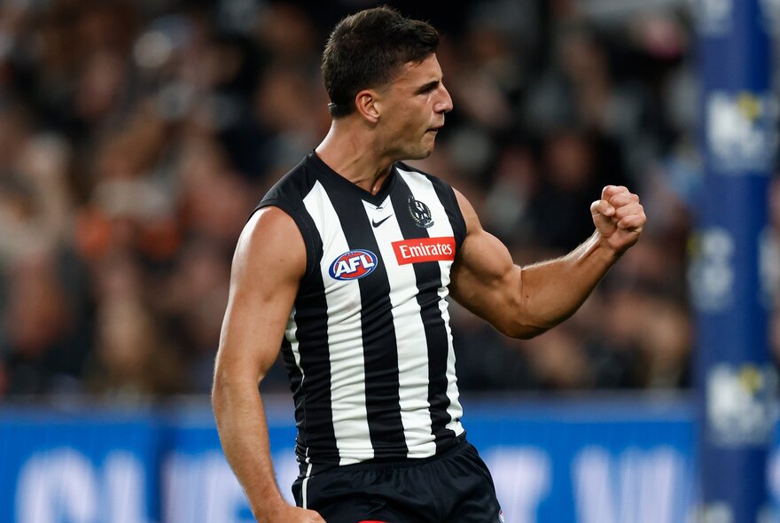 A Collingwood AFL football player with his fist clenched and pumped during a match.