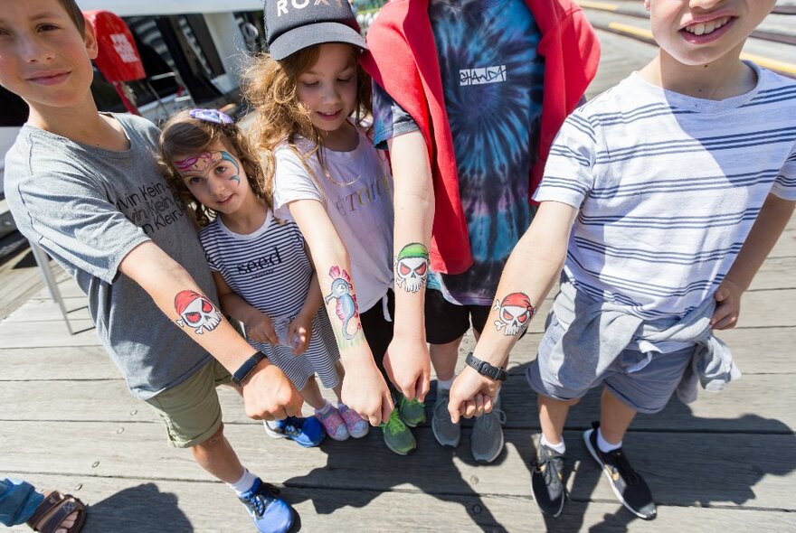 Kids holding their arms out with pirate tattoos. 