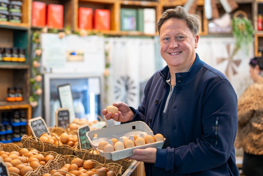 Chef Darren Purchese holding a dozen eggs in a market setting.