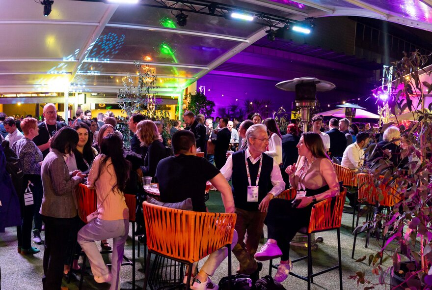 People seated at tables in a large venue space.