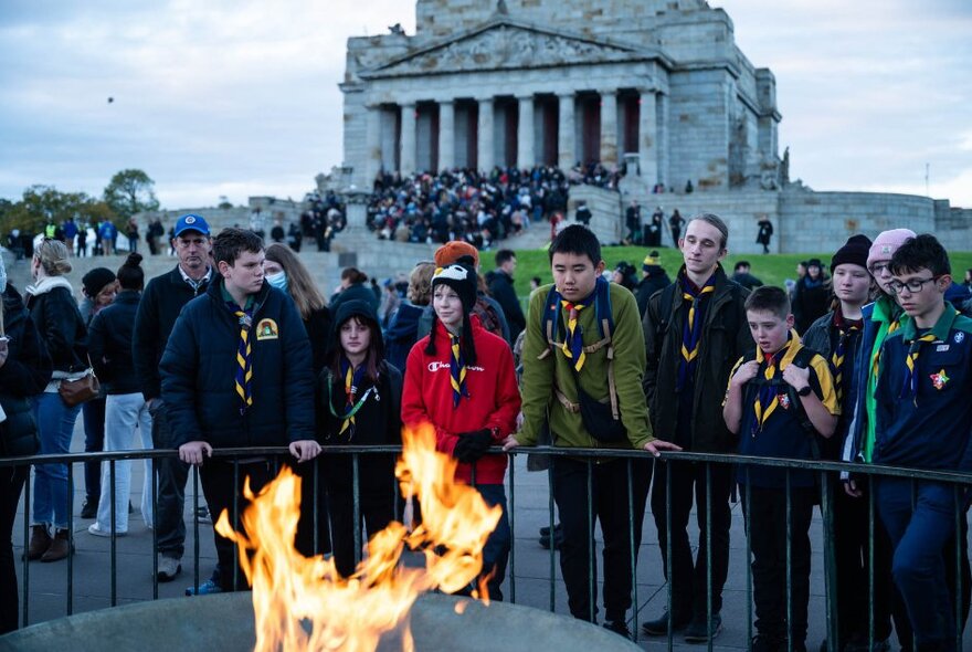 People gathered around the Eternal Flame with the Shrine of Remembrance in the background. 