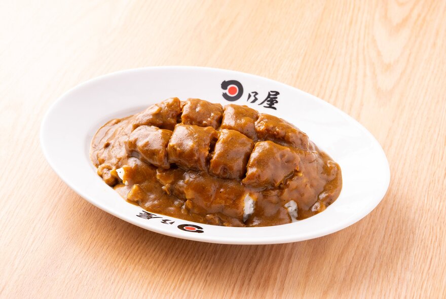 Japanese curry in a white bowl on a wooden surface.