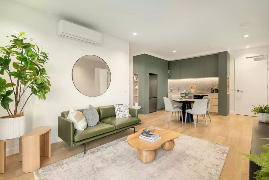 An open-plan apartment interior featuring a living area that flows into a kitchen and dining space.